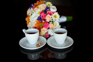 Fototapeta na wymiar Close up of engagement rings, rose flower bouquet and coffee on table. 