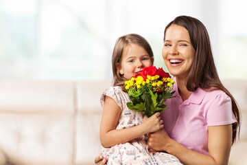 Fototapeta na wymiar Loving little child hugging happy mom and greeting with a bouquet