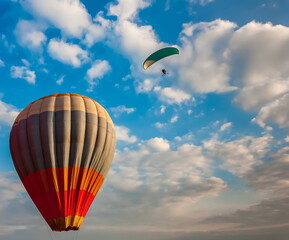 Balloon and paraglider on the background of blue sky with white clouds in summer