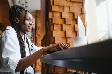 Focused young african american businesswoman or student looking at laptop, serious black woman working or studying with computer doing research or preparing for exam online