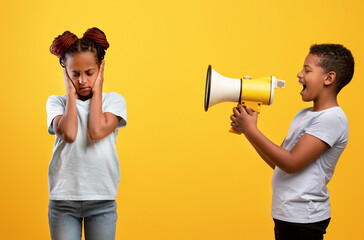 Naughty afro-american boy yelling at his sister, using megaphone