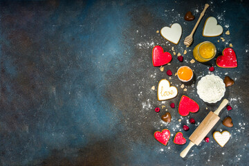 Valentine day sweet cooking background. Baking ingredients and utensils - flour, rolling pin, heart shaped biscuits, eggs. Making cute Valentine`s sweet gift. Top view copy space on dark background