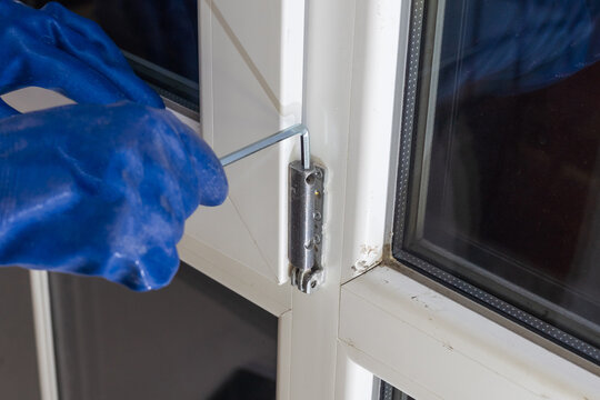 Handsome Man Using A Screwdriver To Install A Window Handle And Looking At The Camera. Making A House Cozy And Warm