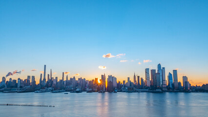 Stunning sunrise over Manhattan skyline with saturated colors and sun rays camping from the sun.