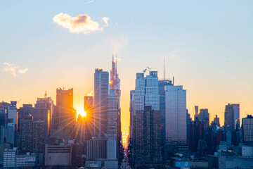 Stunning sunrise over Manhattan skyline with saturated colors and sun rays camping from the sun.