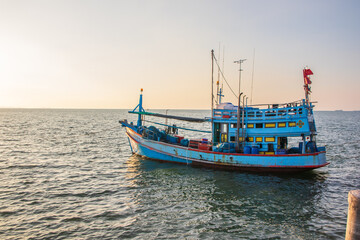 Fototapeta premium In the evening, colorful fishing boats are securely tied down directly at the pier with seaman's ropes and knots