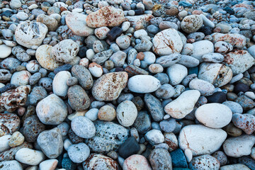 Stones of different shapes, sizes and colors on the seashore, close-up. Background of sea stones.
