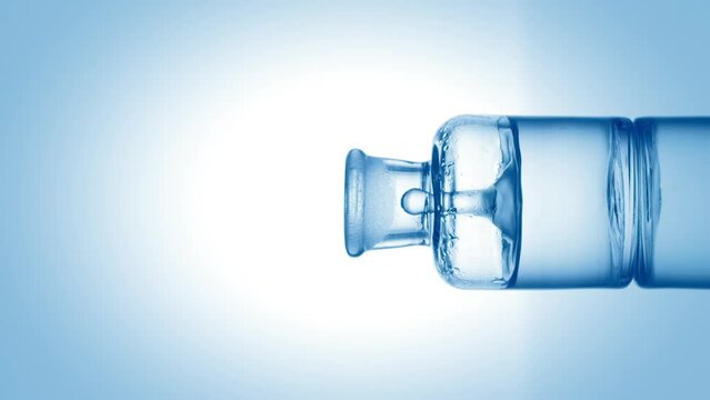 Drop of hypochlorous acid falls into old fashioned bottle with blue transparent fluid on pale blue background | Abstract body care cosmetics with hypochlorous acid mixing concept