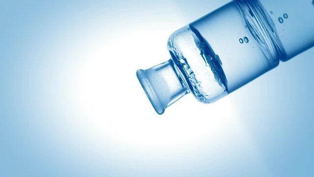 Drop of hypochlorous acid drips into old fashioned bottle with blue transparent liquid on pale blue background | Abstract body care cosmetics with hypochlorous acid formulating concept