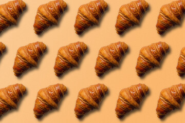 Horizontal croissant pattern with orange background and copy space.