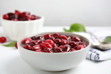 Delicious dogwood jam with berries in bowl on white table, closeup