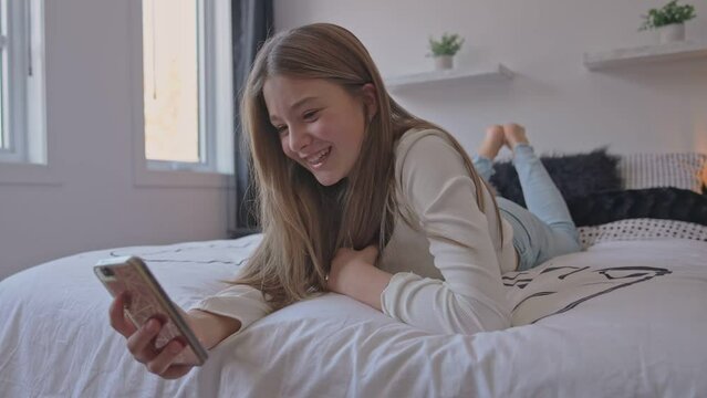 A teenage girl with smartphone on bed	