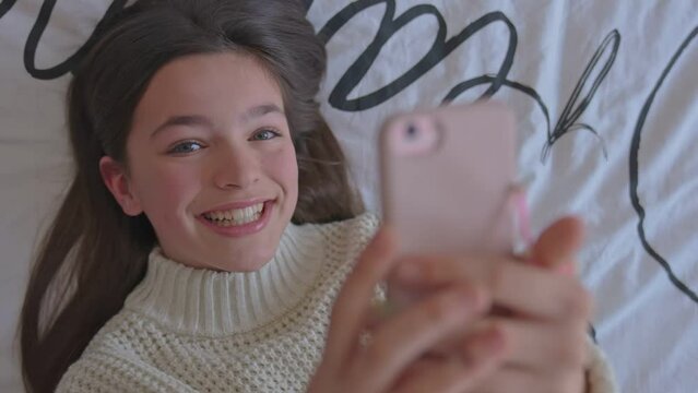 A teenage girl with smartphone on bed	