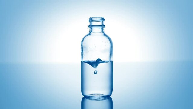 Drop of hypochlorous acid falls down into medical bottle with blue transparent liquid on pale blue background | Abstract body care cosmetics with hypochlorous acid formulating concept