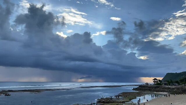 Blue hour at ocean shore. Time lapse of storm clouds at sunset in Bali island at Melasti beach. Seaside evening with gloomy sky. 