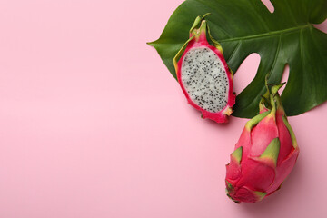 Delicious cut and whole white pitahaya fruits with green leaf on light pink background, flat lay....