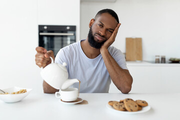 Fototapeta na wymiar Black guy pouring coffee away from cup spilling hot drink