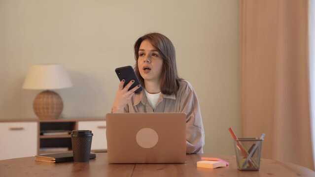 Talks on the phone, works on a laptop at home remotely, writes a message to a client, video communication