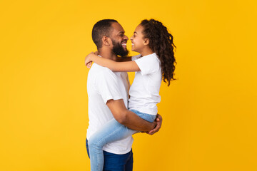 Naklejka premium Cheerful African American Man Carrying Excited Daughter On His Hands