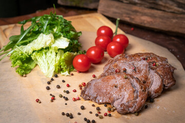 Pork fillets are served with barbecue sauce, soy sauce, cherry tomatoes, lettuce salad with arugula-seeded pepper mixture. Restaurant concept. Restaurant food. Grill concept