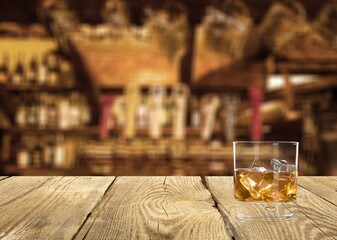 Glass of alcohol whiskey on the bar counter. Blurred interior of bar at the background.