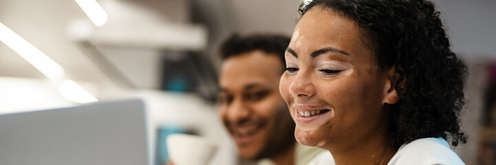 Middle eastern man and woman smiling while working with laptop together