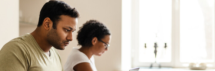 Middle eastern man and woman reading book and working with laptop