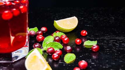 Glass with juice, lime wedge, mint and cranberries