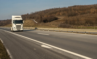 Fototapeta na wymiar White Semi-trailer driving along highway. Goods Delivery by roads. Services and Transport logistics