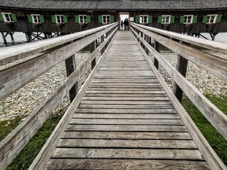Obraz premium Wooden bridge leads straight towards a building