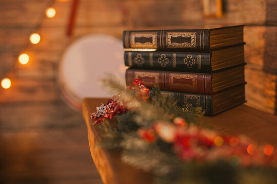 a stack of old vintage books on the fireplace with festive christmas holidays decor at home with cozy evening lighting