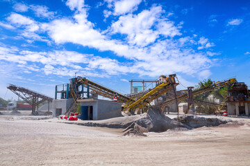 Crushing machinery, cone type stone crusher, conveying crushed granite gravel stone in a quarry open pit mining. Processing plant for crushed stone and gravel. Mining and Quarry mining equipment.