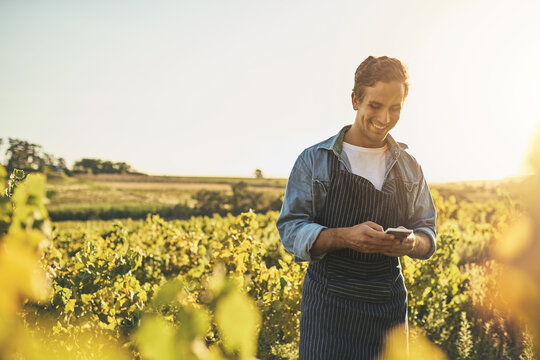 Modern tools for a modern farmer. Shot of a young man using his cellphone while working on a farm.