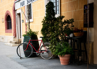Fototapeta na wymiar Red Bicycle Outside of Old European Pub or Cafe