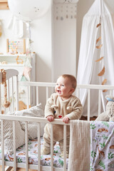 Baby 6 months standing in crib in children's room. Happy motherhood and fatherhood. Maternity hospital and clinic. Father and mother day. Early childhood development, nursery