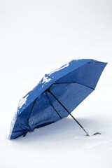 Abandoned blue umbrella on a cold snowy day.