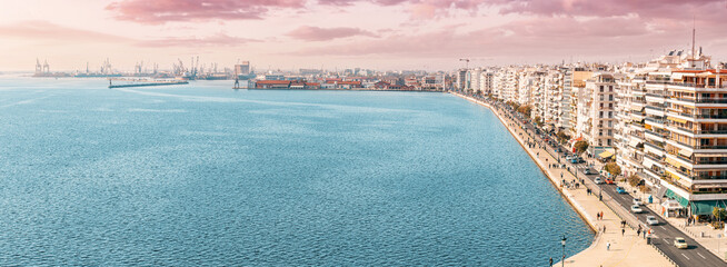 Aerial panorama over the promenade of Thessaloniki city with facades of buildings and a busy cargo sea port from White Tower viewpoint. Visit Greece and sightseeing concept