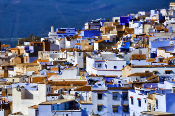 Panorama general de el pueblo de Chefchaouen (Marruecos) con su mayoría de casas azules y blancas con techos de tejas rojas. - obrazy, fototapety, plakaty