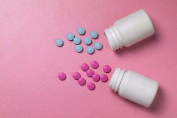 Blue and pink pills spill out of white jars