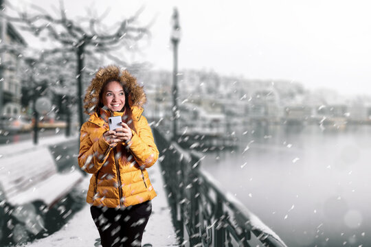 Mujer caminando por rivera de ciudad durante caida de nieve. Fotograf&iacute;a de invierno