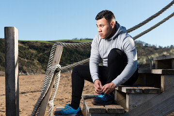 Latin young runner tying laces before training.