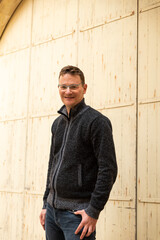 Portrait of a 42 year old white man confident and relaxed standing with a yellow and brown...