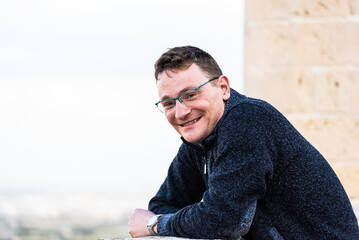 Portrait of a 42 year old white man confident and relaxed standing with a yellow and brown...