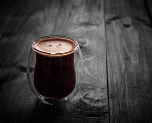 Thermos double glass coffee cup on a wooden background toned in black, aged surface, hot cup of coffee