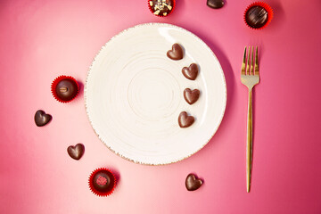 White mock up vintage plate with fork and chocolate hearts. Romantic dinner, Valentines Day concept. Chocolate hearts and decorated sweets.