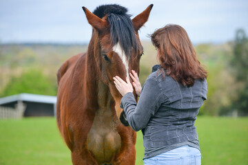 Close up shot of pretty young woman and her bay horse sharing an emotional moment outdoors in field in rural Shropshire UK.