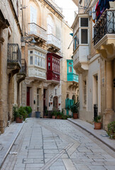 Fototapeta na wymiar Valletta, Malta - 01 06 2022: Narrow street with residential houses in Mediterranean style