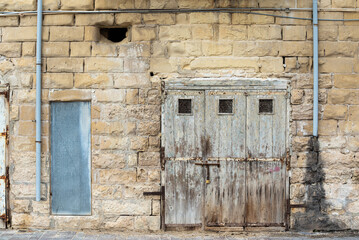 Saint Julian, Malta - 01 07 2022: Worn brown facade and wooden doors at the seaside