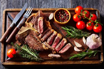 Selbstklebende Fototapeten Steakhouse fried sliced porterhouse steak on a wooden board  © myviewpoint