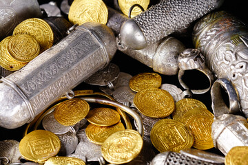 A lot of stacked gold bullion bars and gold coins and silver coins in a treasure sack. Treasure...